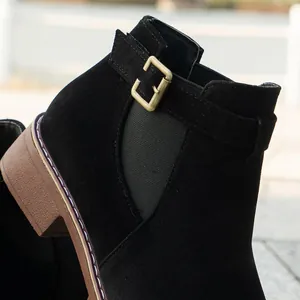 Macro view of black suede women's ankle boot with golden buckle and elastic panel