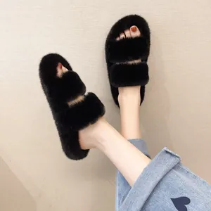 Detailed view of women wearing black fluffy two-strap faux fur platform slippers