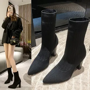 Detalle de botines de calcetín de punto negro con elegantes tacones gruesos para mujer