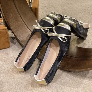 Detailed view of vintage black ballet flats with gold toe and bow accent.