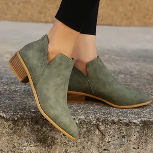 Close-up of olive green pointed-toe ankle boots with low heel on stone ground