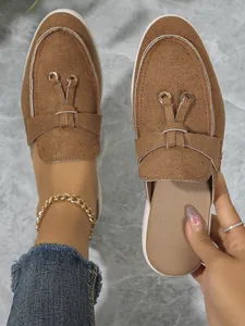 Gros plan sur d'élégantes mules en daim marron avec nœud décoratif et détails dorés