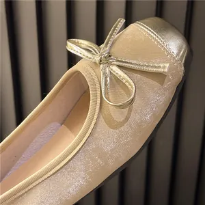 Close-up of retro ballet flats featuring gold toe caps and delicate bow details