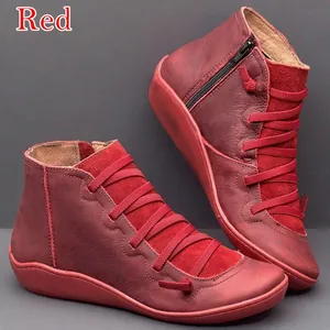 Détail de bottines plates en cuir rouge avec fermeture éclair latérale et lacets