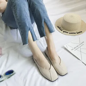 Dettaglio di ballerine beige a punta quadrata con cuciture delicate su fondo bianco.