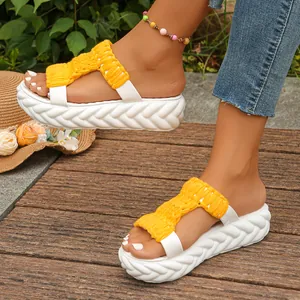 Detailed view of women's yellow woven platform sandals worn on a wooden deck outdoors