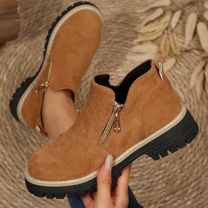 Gros plan de bottines en daim beige avec fermeture éclair et semelle crantée.
