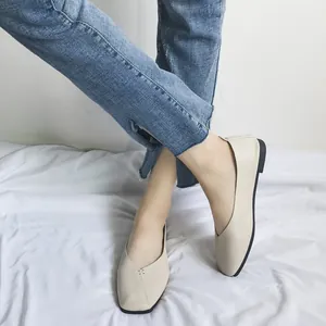 Eleganti mocassini piatti beige a punta quadrata da donna abbinati a jeans blu