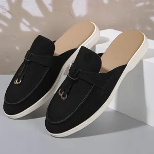 Vue latérale de mules noires en tissu texturé avec boucle métallique et semelle plate blanche