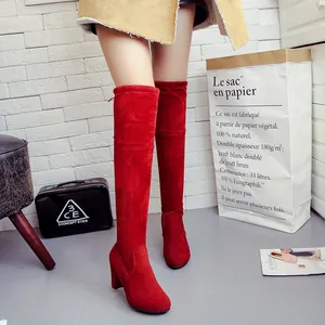 Vibrant red suede over-the-knee boots with chunky high heels in lifestyle setting.