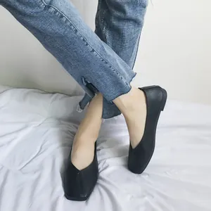 Dettaglio di ballerine nere a punta quadrata con scollatura a V indossate con jeans