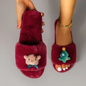 Close-up detail of burgundy plush Christmas slippers featuring reindeer and tree ornaments