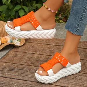 Detail view of orange knitted upper and thick white platform sole on trendy women sandals.
