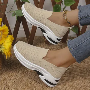 Vista detallada de zapatillas de malla tejida beige para mujer en pie de modelo.