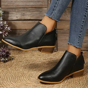 Detail view of black pointed-toe ankle boots with low block heel and side cutout.