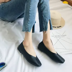 Dettaglio di ballerine nere a punta quadrata indossate su uno sfondo bianco in stile