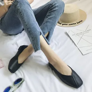 Vista dettagliata di ballerine nere a punta quadra abbinate a jeans blu con spacco.