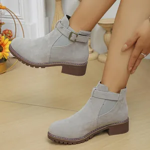 Detailed view of grey suede ankle boots featuring buckle and elastic side panels on model