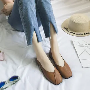 Primo piano di ballerine marroni a punta quadra indossate con jeans su tessuto