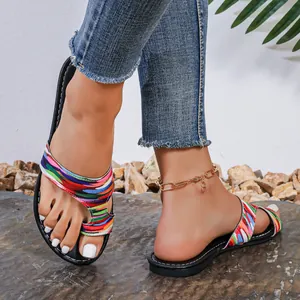 Gedetailleerde close-up van kleurrijke platte sandalen met teenlusontwerp op voeten
