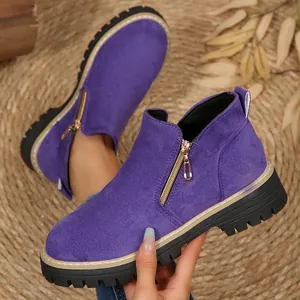 Détail de bottines en daim violet avec fermeture éclair dorée et semelle noire épaisse