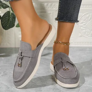 Gros plan de mules pointues en daim gris portées avec une chaîne de cheville