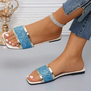 Detailed view of blue glitter square toe flat sandals with gold trim on model feet