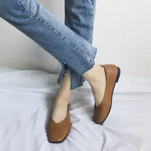 Dettaglio di scarpe basse marroni a punta quadrata indossate con jeans su tessuto