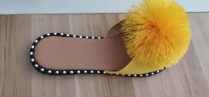 Macro view showing the vibrant yellow tassel detail on a minimalist women's flat slide sandal