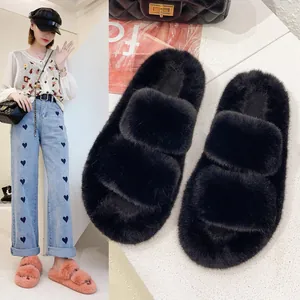 Close-up detail of black plush platform slippers with a model wearing pink shoes.