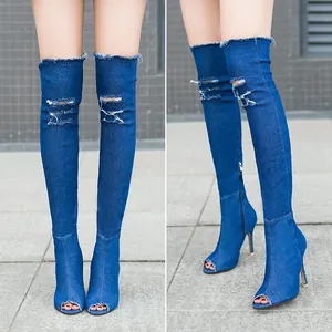 Detailed view of ripped denim over-the-knee boots with stiletto heel and peep-toe