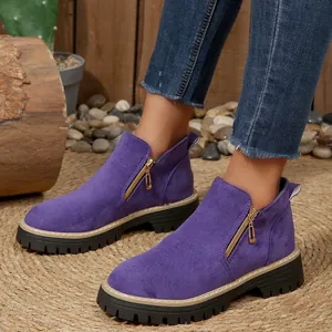 Gros plan de bottines en daim violet avec fermeture éclair dorée et semelle crantée