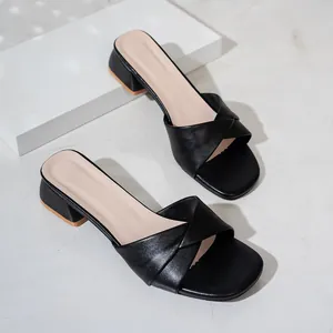 Vista detallada de sandalias retro negras con tacón de bloque y diseño elegante de tira cruzada
