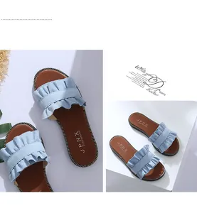 Gros plan des mules à volants bleu clair avec une semelle marron plate confortable.
