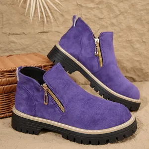 Détail de bottines en daim violet avec fermeture éclair latérale et semelle épaisse.