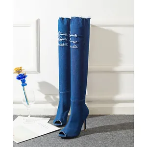 Side view of peep-toe denim over-the-knee boots with high stiletto heels and ripped details.