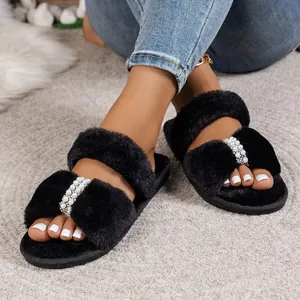 Eleganti pantofole in ecopelliccia nera con perle e strass indossate ai piedi.