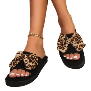 Stylish women's black fuzzy slippers featuring a large leopard print bow and thick sole