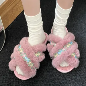 Detailed view of pink fluffy criss-cross slippers with dainty floral embroidery.