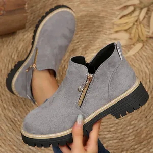 Bottines en daim gris avec fermeture éclair latérale et semelle crantée noire épaisse.