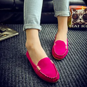 Mocasines de ante rosa con hebillas doradas en los pies y fondo de alfombra gris