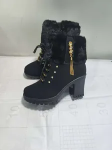 Detailed view of black high heel winter boots with fur trim and rhinestone tassels.