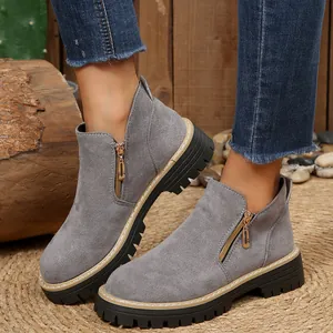 Gros plan de bottines en daim gris avec fermeture éclair dorée et semelle crantée