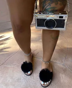 Stylish black flat slippers with oversized faux fur pom-poms for summer street wear.