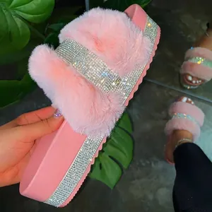 Close-up detail of pink faux fur slides featuring a sparkling rhinestone platform