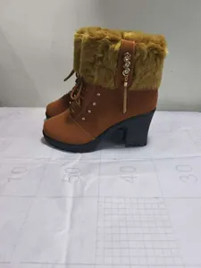 Detailed view of brown high-heeled boots with faux fur trim and rhinestone tassels