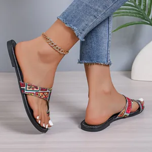 Close-up van dames met platte sandalen met patroon en teenring in casual setting