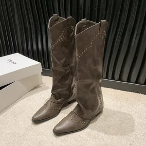 Detailed view of vintage brown knee-high cowboy boots with decorative metallic rivets