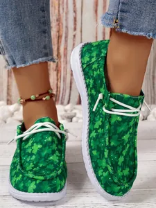 Nahaufnahme der grünen Leinenschuhe mit Kleeblatt-Print zum Hineinschlüpfen für Damen