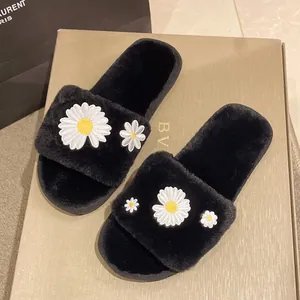 Detailopname van zwarte pluizige pantoffels met witte madeliefjesborduursels op pluche